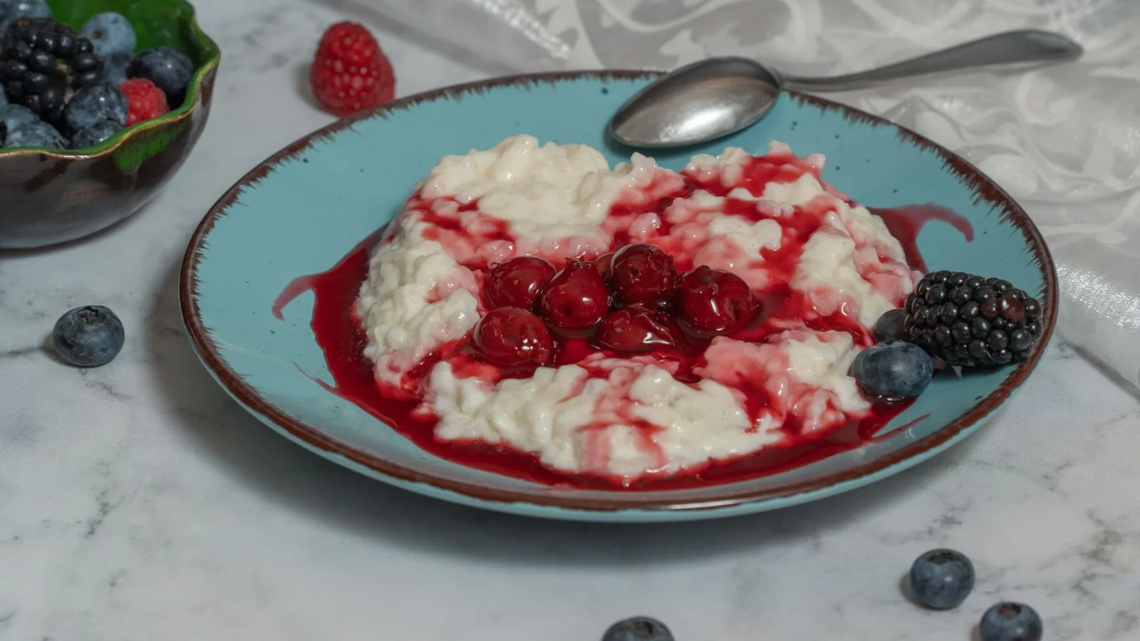 Creamy rice porridge topped with fresh berries and cherry sauce, perfect for breakfast or dessert.