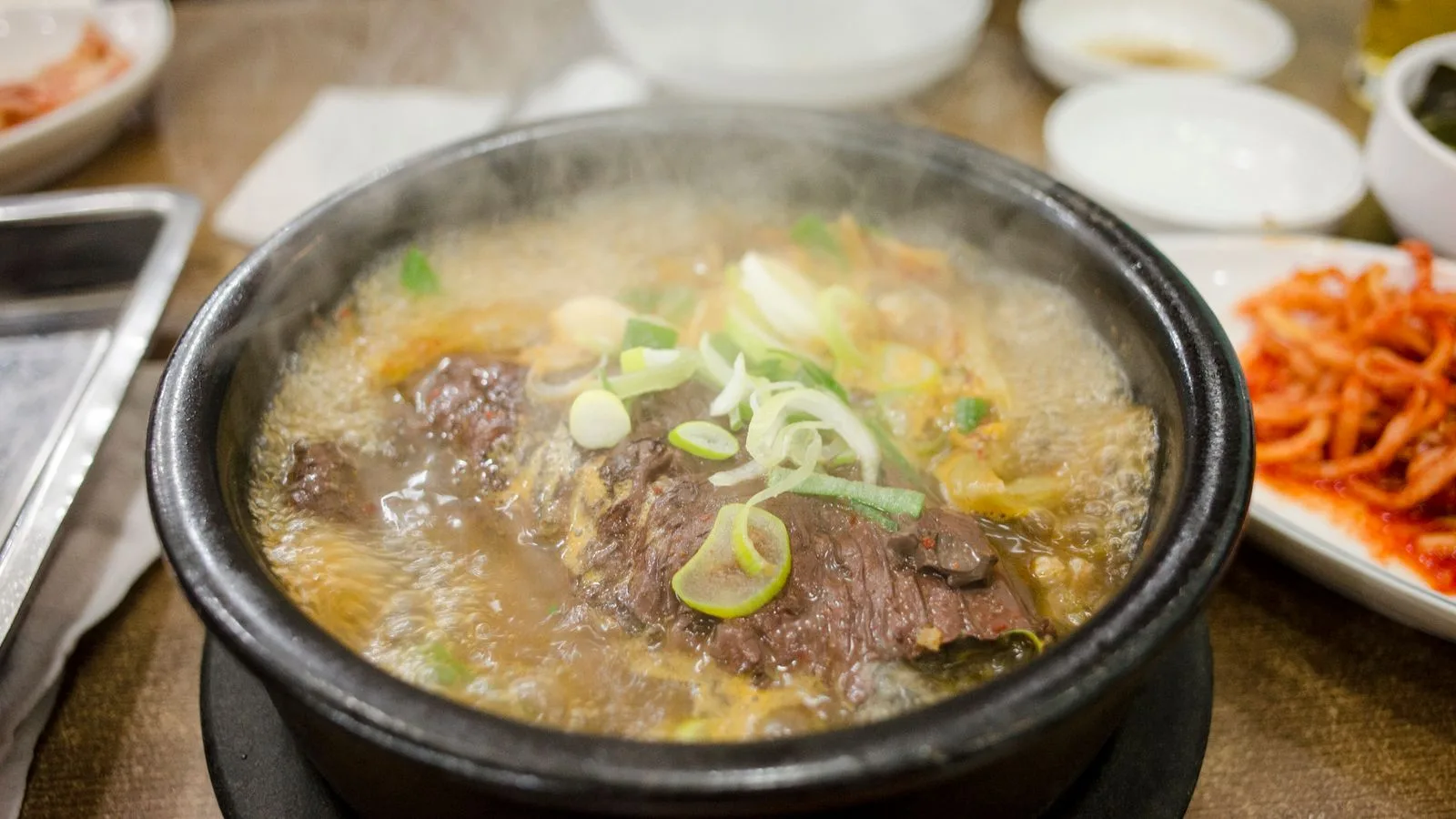 Delicious steaming beef stew in a traditional Korean hot stone pot, garnished with fresh scallions.